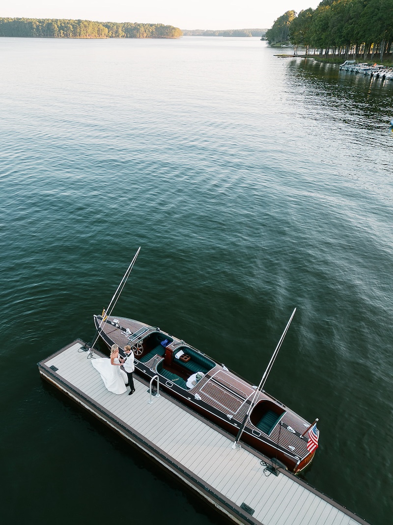 Aerial photo of bride and groom on dock with vintage boat. Elegant wedding at the Ritz-Carlton Lake Oconee in Georgia. Sarah Bradshaw Photography.
