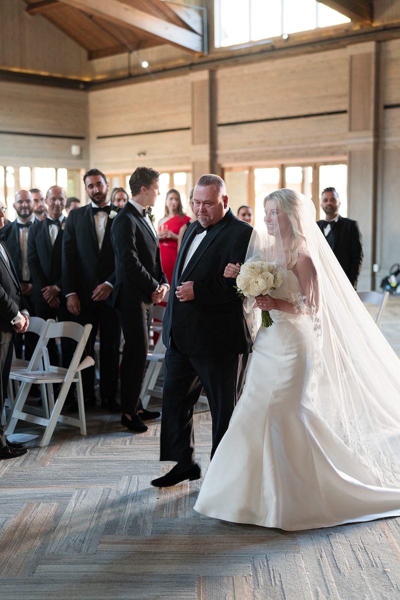 Bride and father walk down the aisle in ballroom. Elegant wedding at the Ritz-Carlton Lake Oconee in Georgia. Sarah Bradshaw Photography.