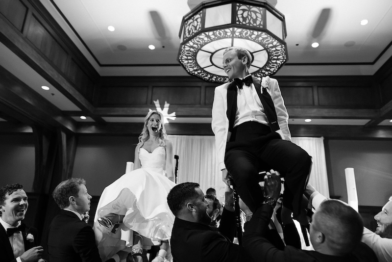 Bride and groom lifted on chairs for hora at wedding reception. Elegant wedding at the Ritz-Carlton Lake Oconee in Georgia. Sarah Bradshaw Photography.