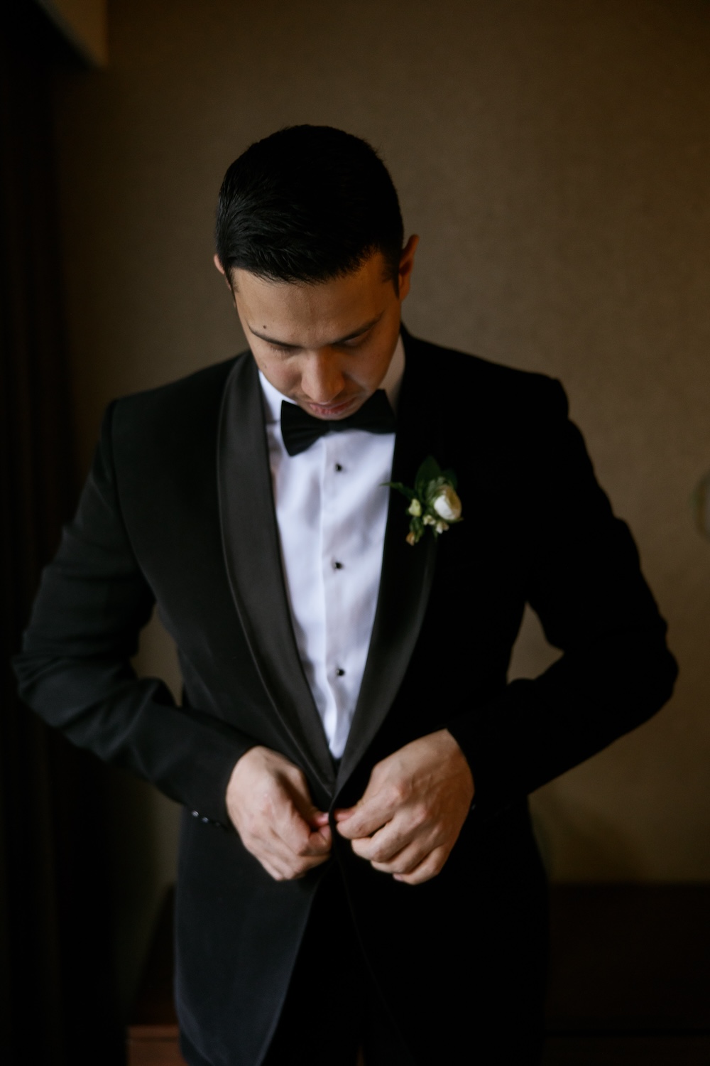 Groom putting on tuxedo jacket on wedding morning. Modern Washington DC wedding at National Museum of Women in the Arts. Sarah Bradshaw Photography.
