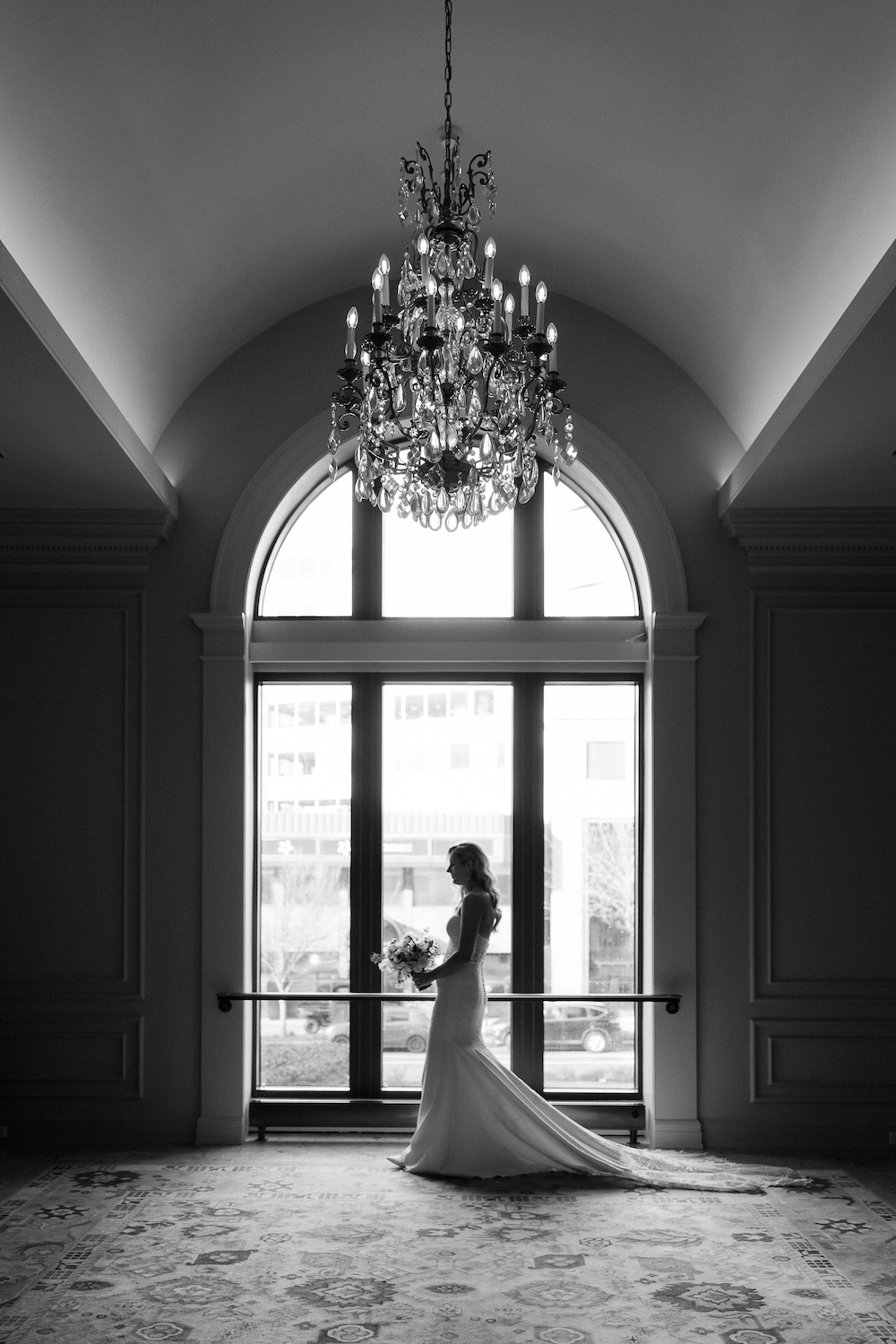 black and white bridal portrait. bride standing in front of large window with chandelier. Modern Washington DC wedding at National Museum of Women in the Arts. Sarah Bradshaw Photography.