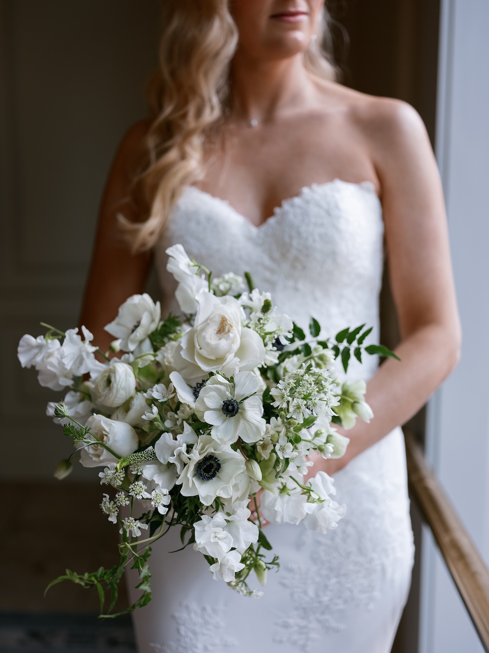 Bride in strapless lace wedding dress holds white and green bouquet. Modern Washington DC wedding at National Museum of Women in the Arts. Sarah Bradshaw Photography.