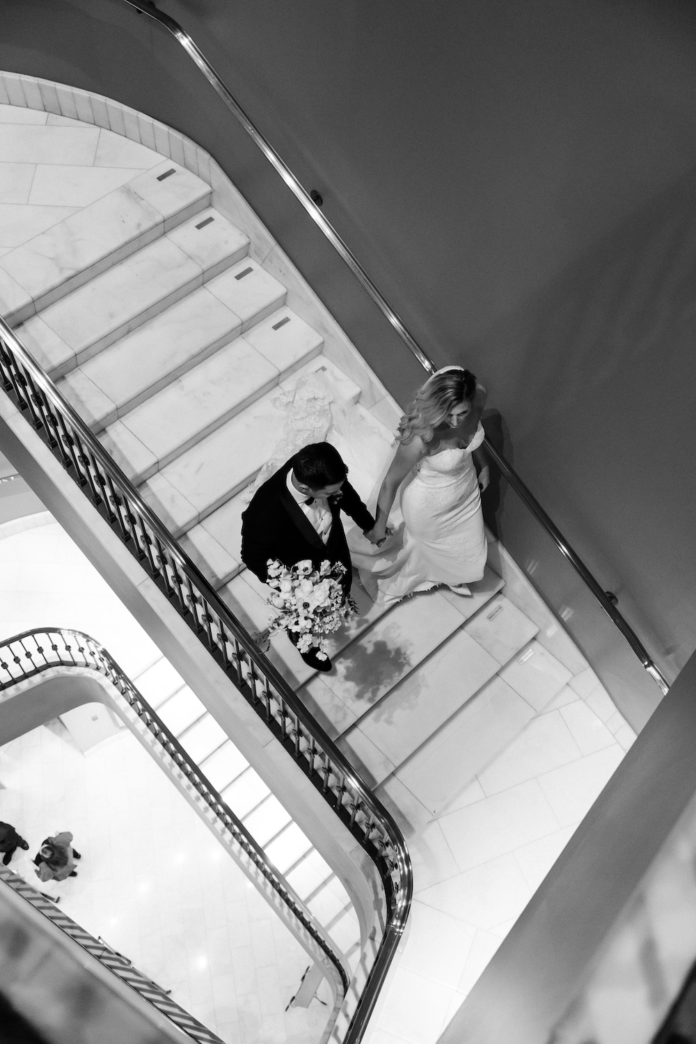 bride and groom walking down elegant staircase. Modern Washington DC wedding at National Museum of Women in the Arts. Sarah Bradshaw Photography.