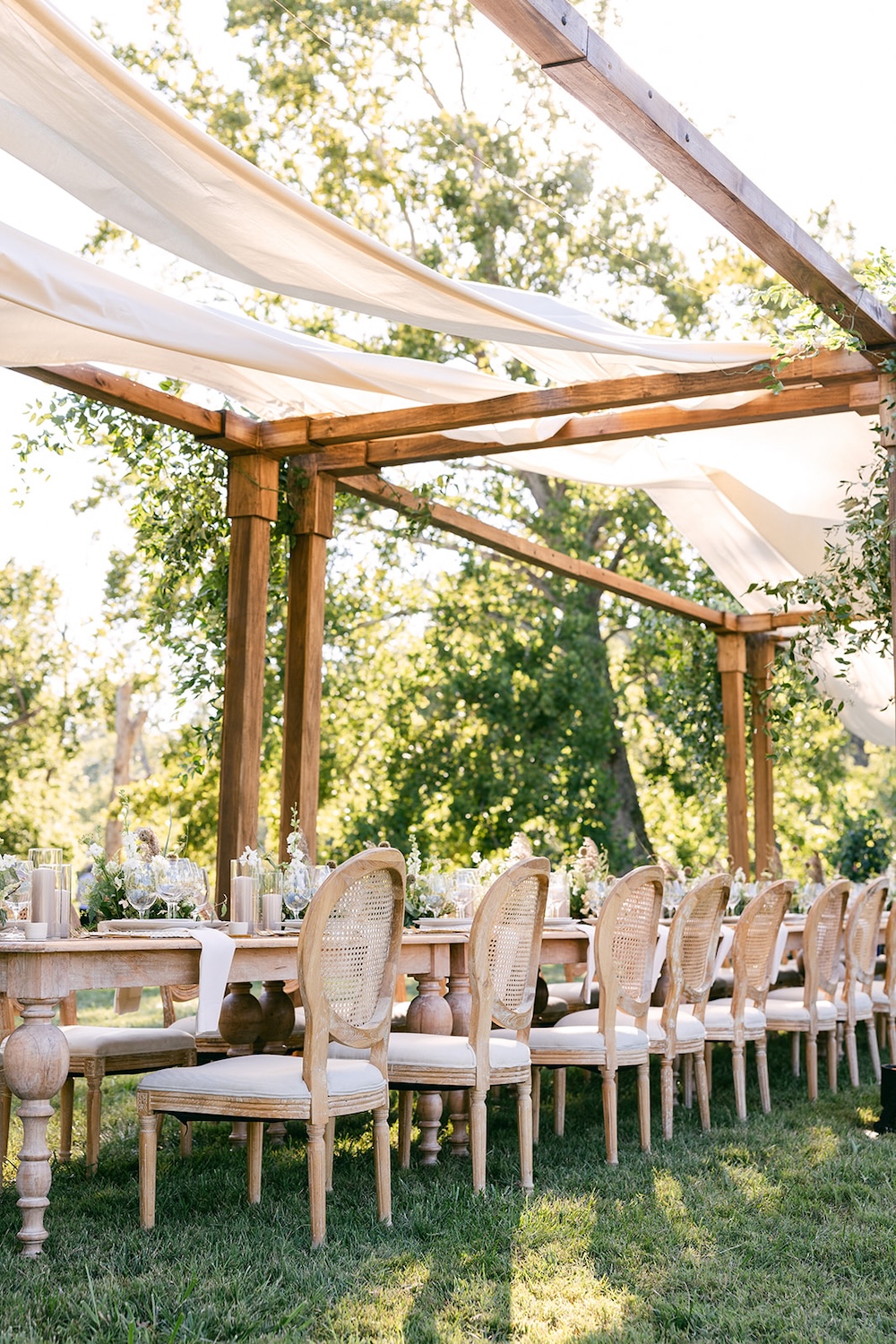 Rattan dining chairs, farmhouse style tables for alfresco tented dinner. Milestone birthday party celebration weekend in Middleburg, Virginia. Sarah Bradshaw Photography.