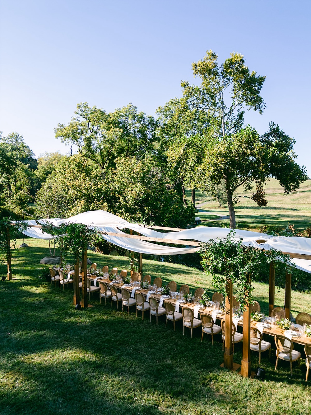 Alfresco dinner with farmhouse tables, tented dinner. Elevated boho chic table design. Milestone birthday party celebration weekend in Middleburg, Virginia. Sarah Bradshaw Photography.