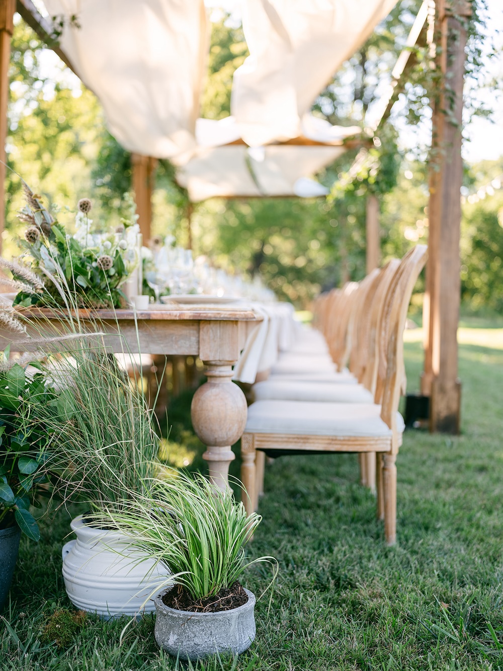 Potted plants party decor. Farmhouse style dinner tables, rattan chairs. Milestone birthday party celebration weekend in Middleburg, Virginia. Sarah Bradshaw Photography.