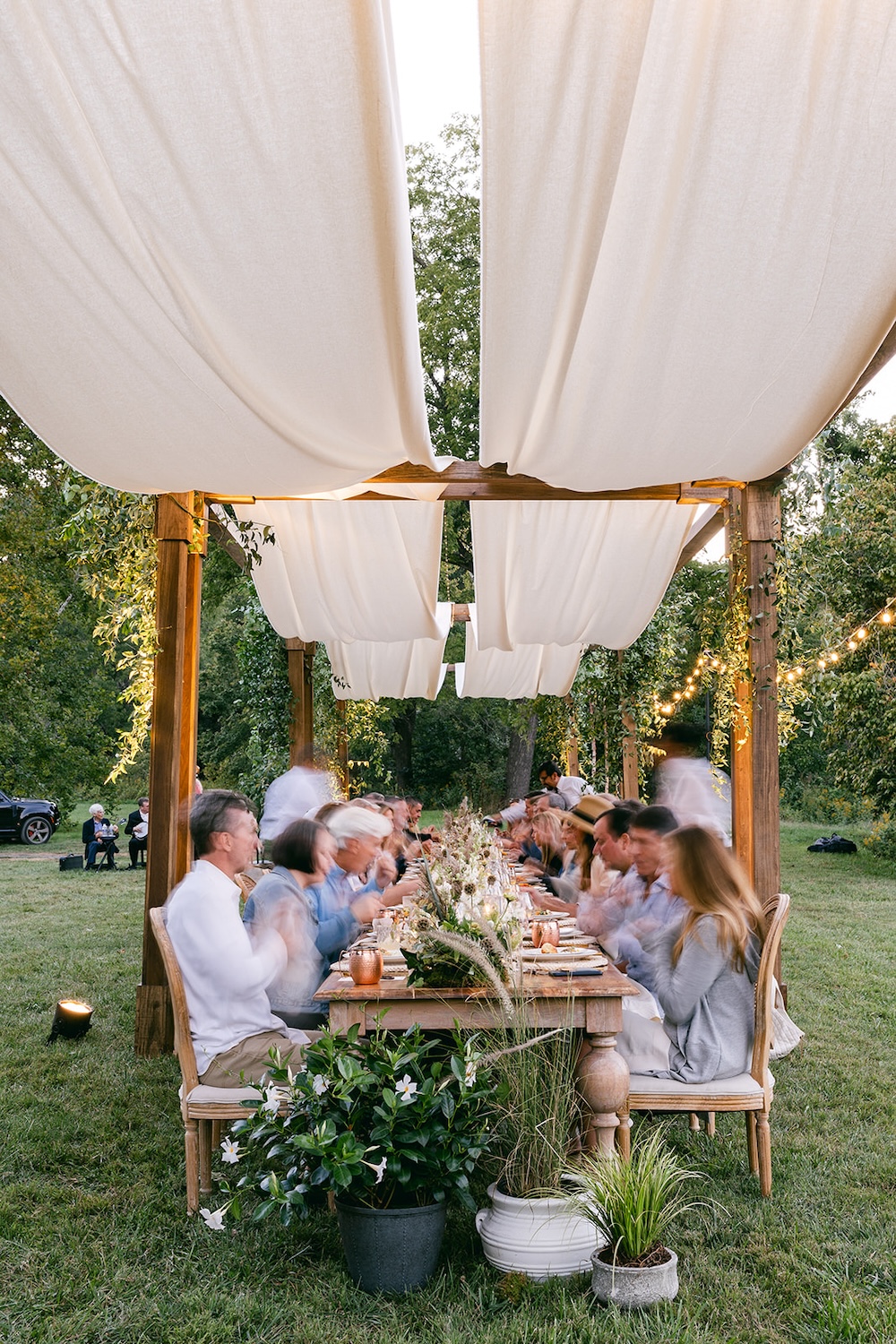 Alfresco dinner at farmhouse tables under rustic chic tent. Milestone birthday party celebration weekend in Middleburg, Virginia. Sarah Bradshaw Photography.