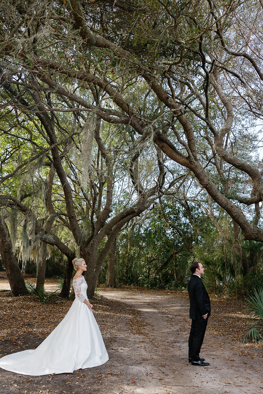 Bride and groom prepare for first look wedding reveal in grove of oak trees. Classic Black Tie wedding in Georgetown, SC. Sarah Bradshaw Photography