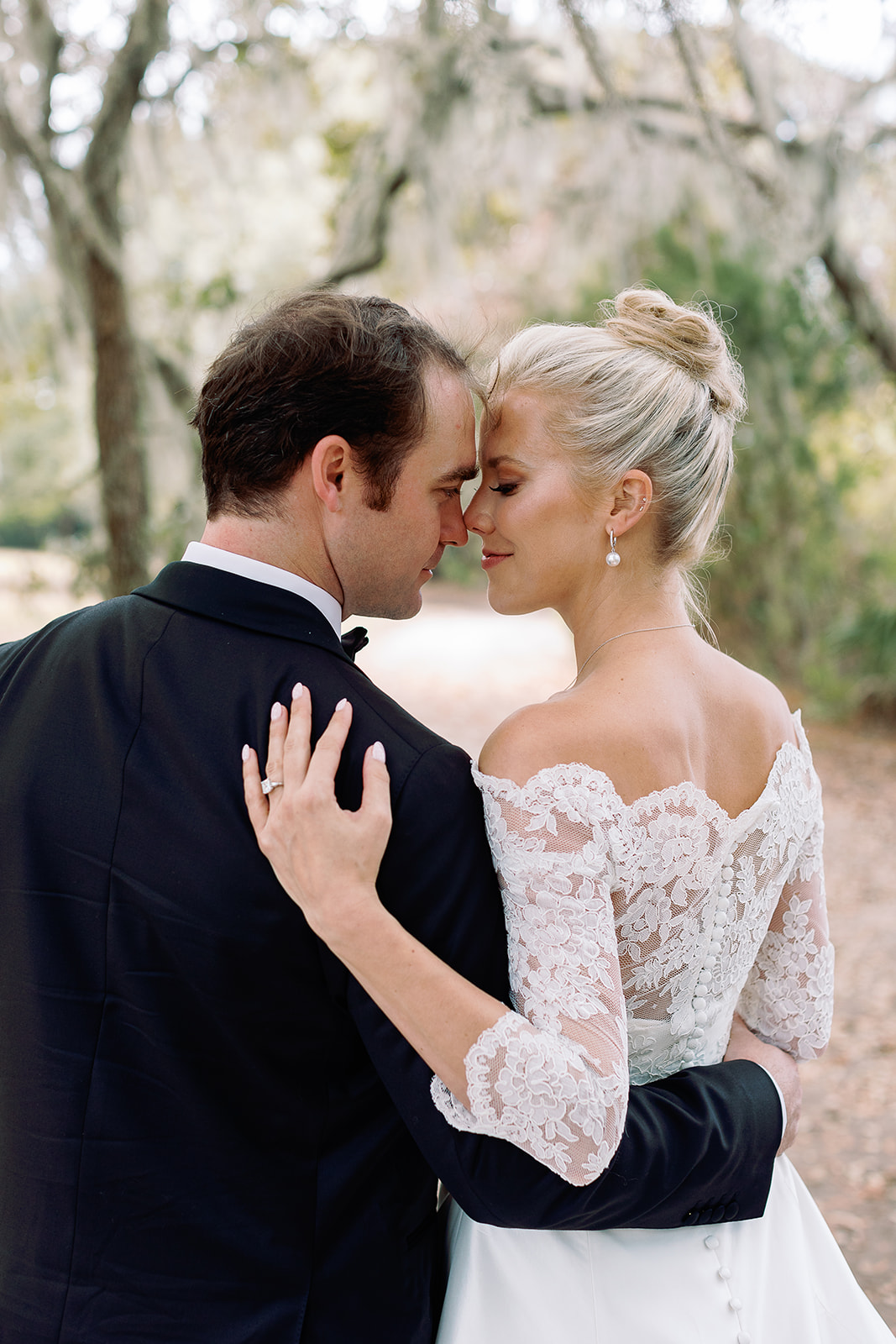 Portrait of bride and groom from behind, lace detailing bridal dress. Classic Black Tie wedding in Georgetown, SC. Sarah Bradshaw Photography