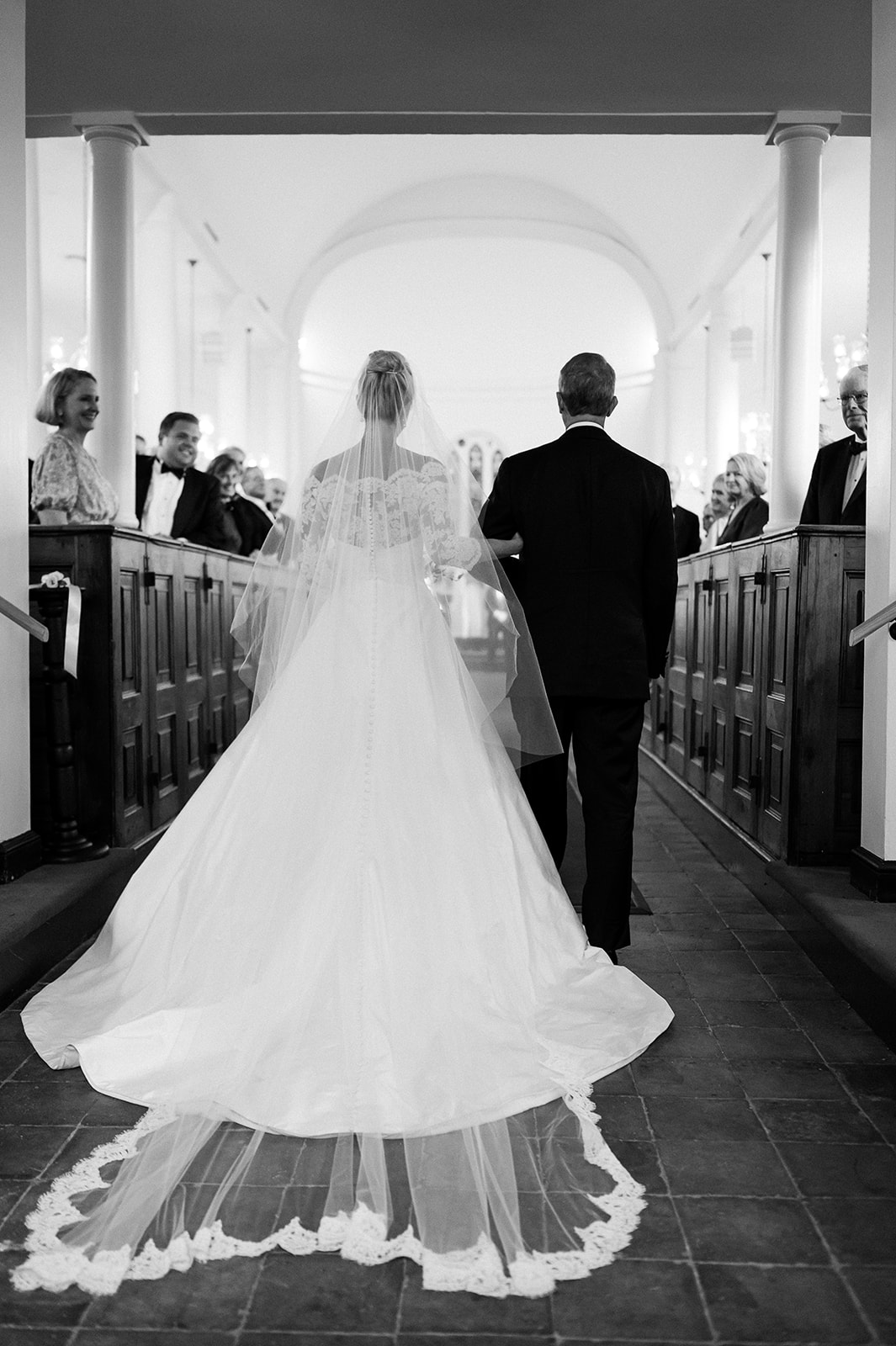 Portrait from behind of bride and father walking down wedding aisle. Classic Black Tie wedding in Georgetown, SC. Sarah Bradshaw Photography