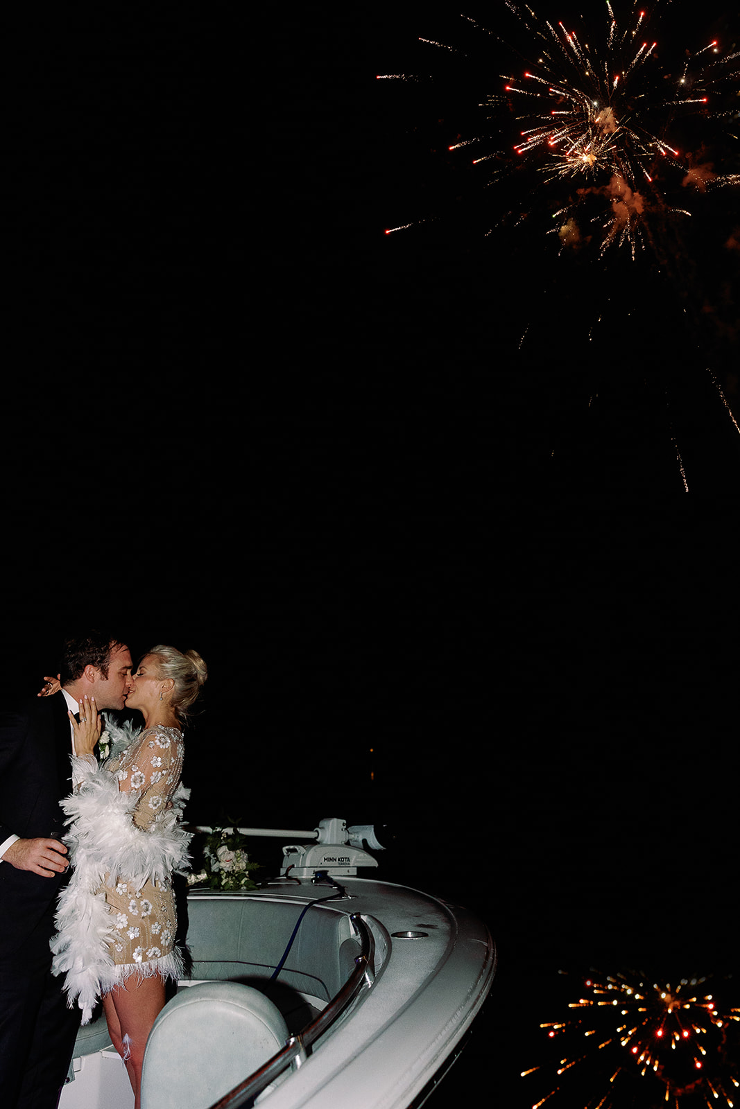 Bride and groom kiss on a boat while fireworks go off in background. Classic Black Tie wedding in Georgetown, SC. Sarah Bradshaw Photography