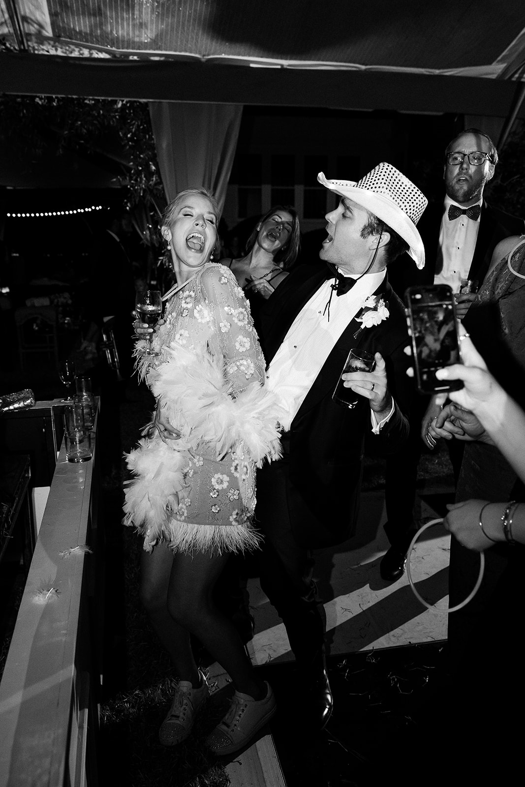 Bride in mini reception dress with sparkle and fringe dances with groom in cowboy hat at wedding reception. Classic Black Tie wedding in Georgetown, SC. Sarah Bradshaw Photography