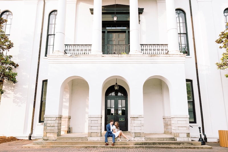 couple sitting in archway of historic building. southern wedding engagement session, sarah bradshaw photography.