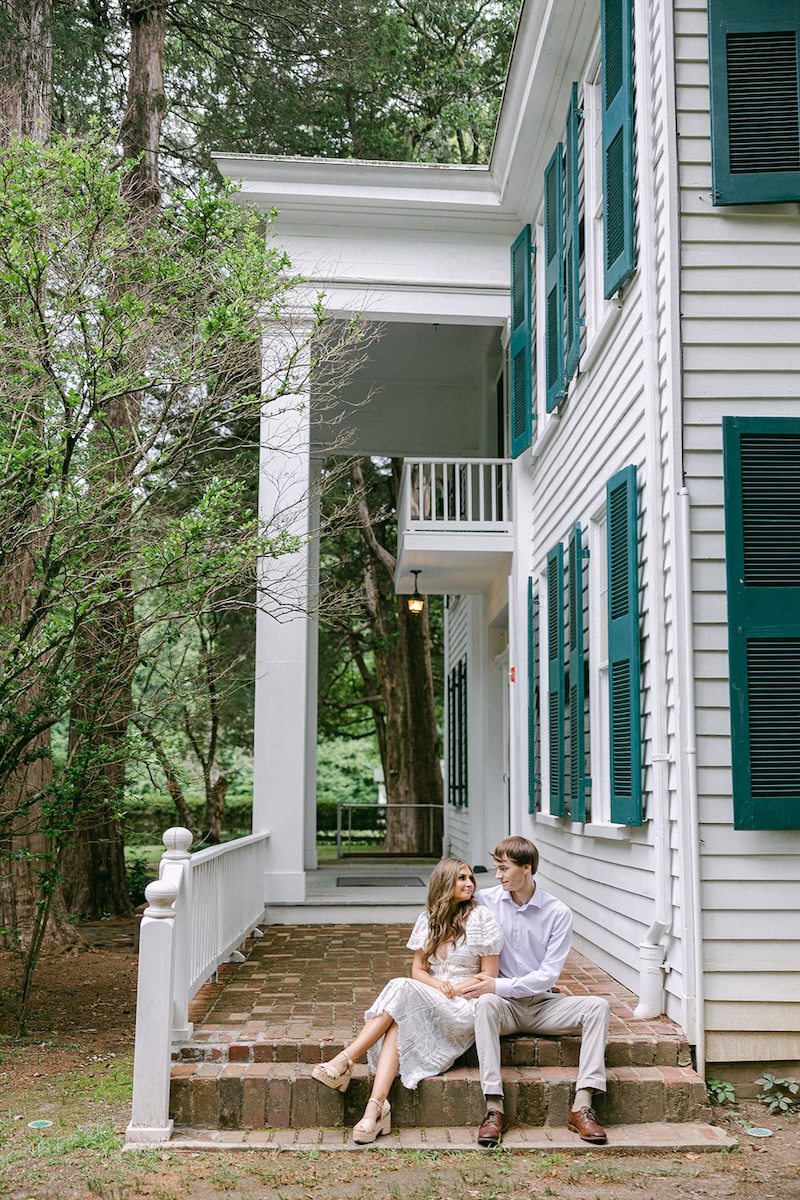 couple sits on stairs of home. southern wedding engagement session, sarah bradshaw photography.