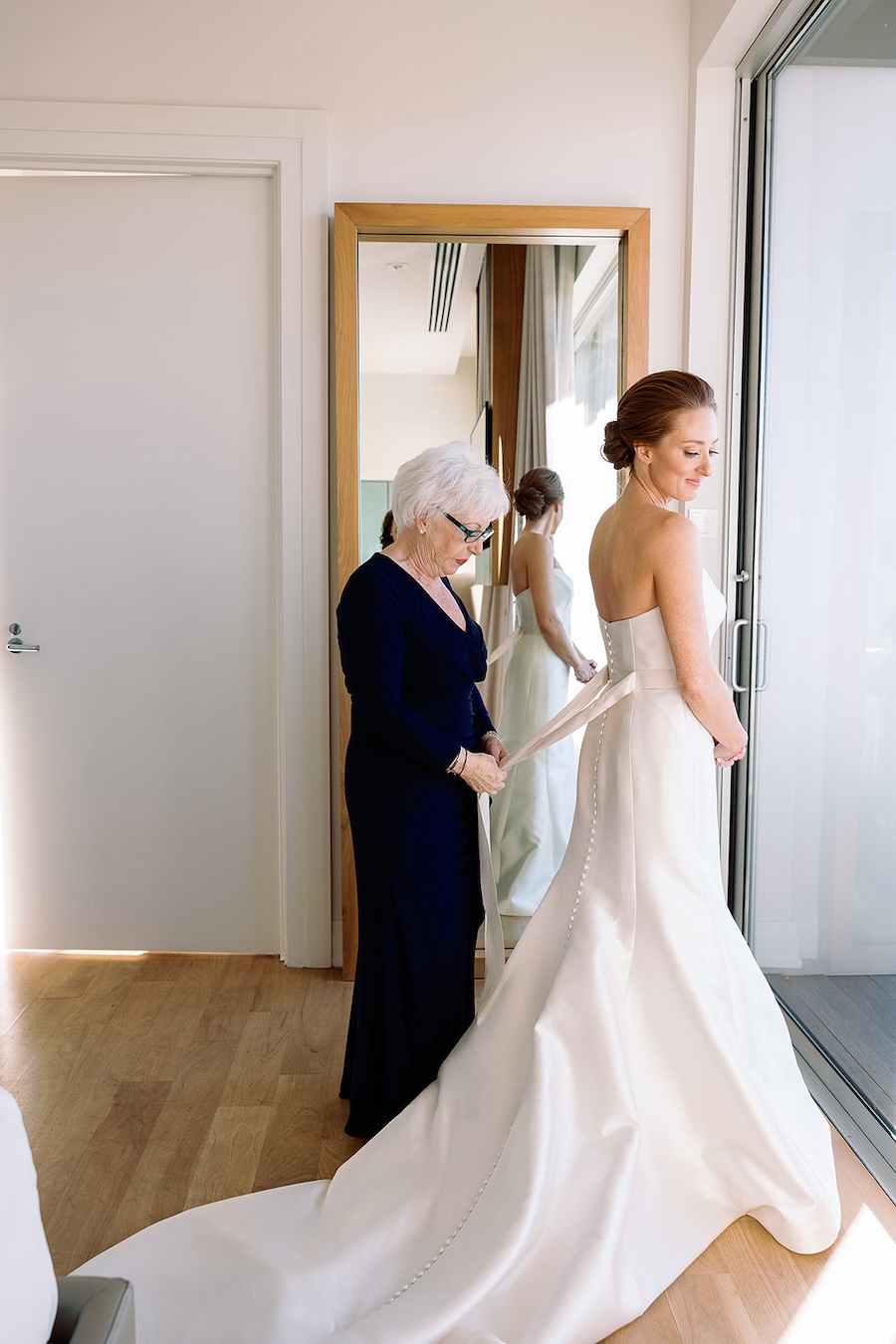 bride getting sash tied on wedding dress. Timeless winter wedding, anderson house, washington dc, sarah bradshaw photography.