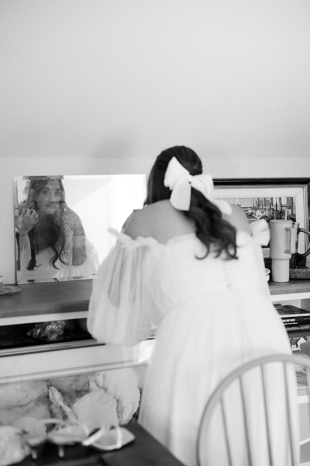 Bride getting ready looks in mirror on wedding morning. Bow in hair. Tented, private home, spring wedding in South Carolina. Sarah Bradshaw Photography