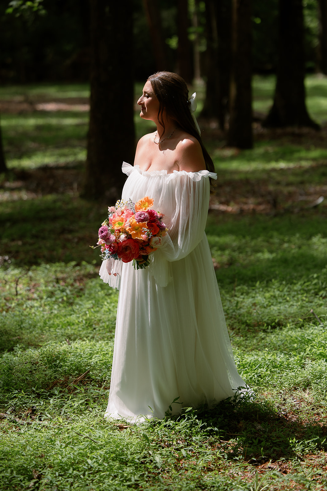 portrait of bride with sunlight coming through trees. off shoulders long sleeve tulle wedding dress, colorful bouquet. spring wedding in south carolina. Sarah Bradshaw Photography