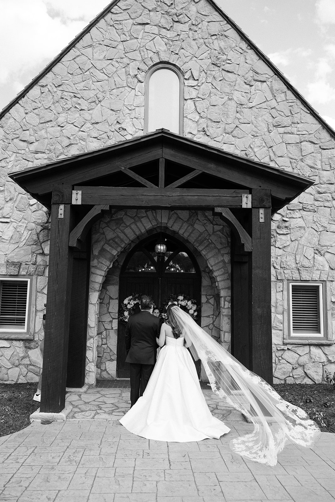 black and white portrait of bride and father walking into wedding chapel. elegant south carolina spring wedding. sarah bradshaw photography