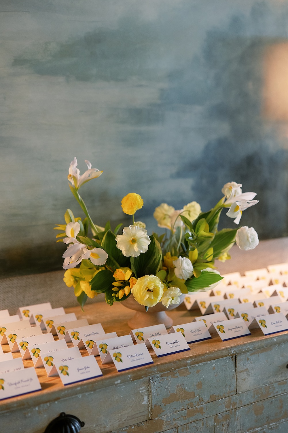 Escort card display with white and yellow floral arrangement.  Italian inspired wedding rehearsal dinner in Greenville, SC. Sarah Bradshaw Photography