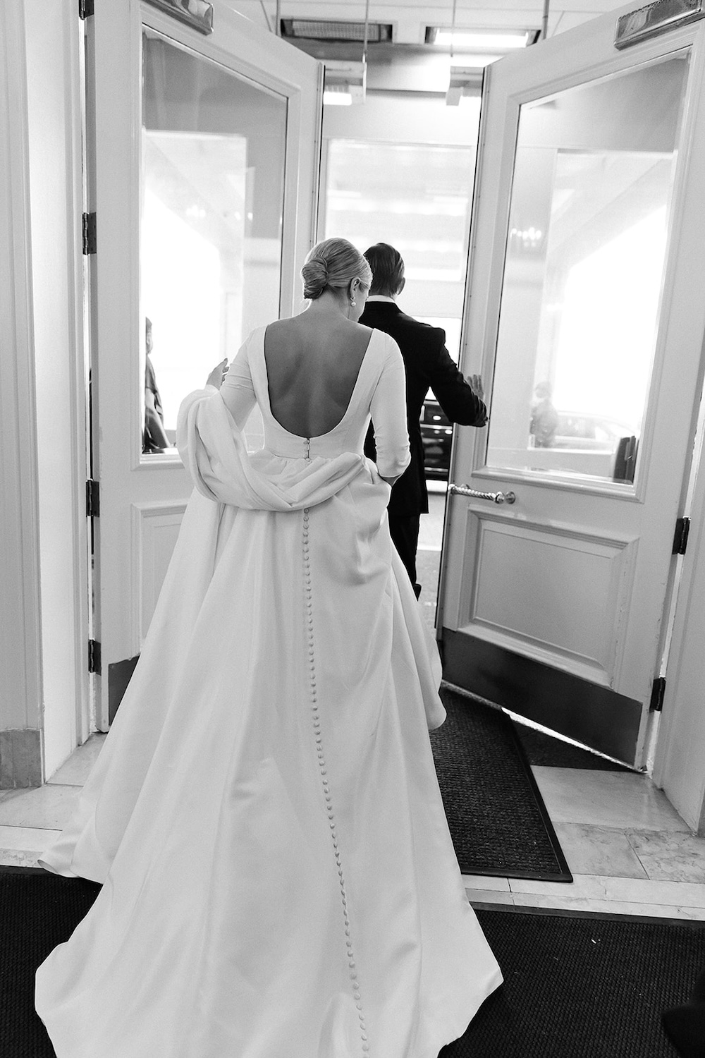 bride in open back wedding dress with buttons down dress skirt walks through doorway. Classic timeless winter wedding, woodlawn manor, alexandria va. Sarah bradshaw photography