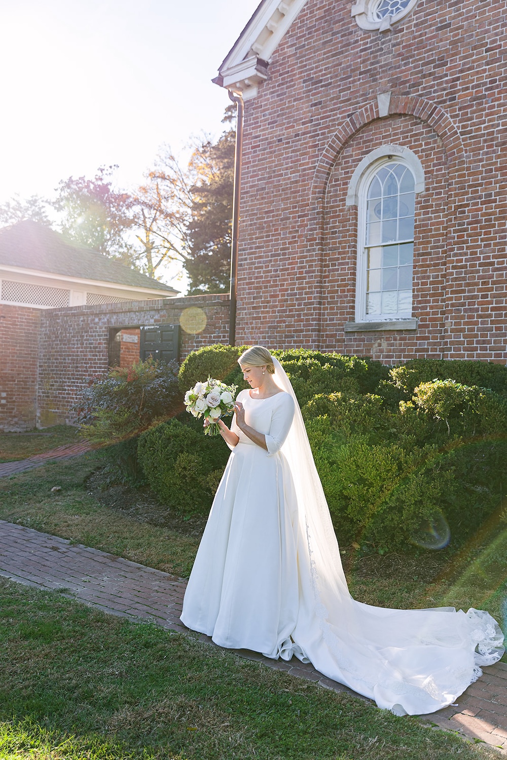 bridal portrait looking at floral bouquet. bride in three quarter sleeve wedding dress. Classic timeless winter wedding, woodlawn manor, alexandria va. Sarah bradshaw photography