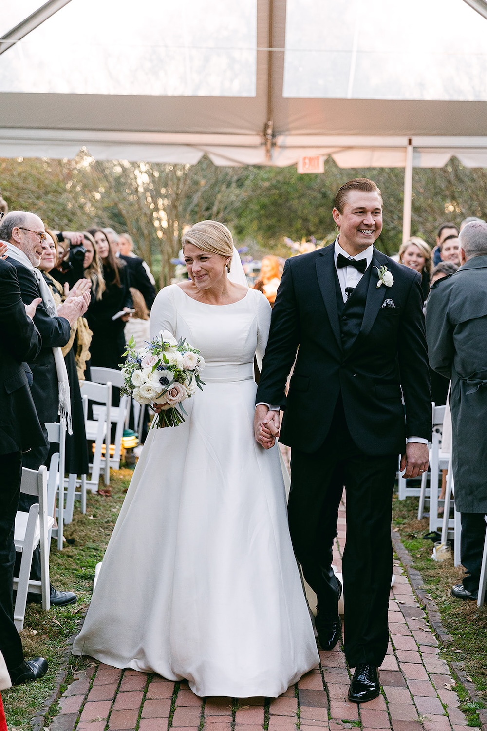 bride and groom smiling walking down the aisle in wedding tent. Classic timeless winter wedding, woodlawn manor, alexandria va. Sarah bradshaw photography