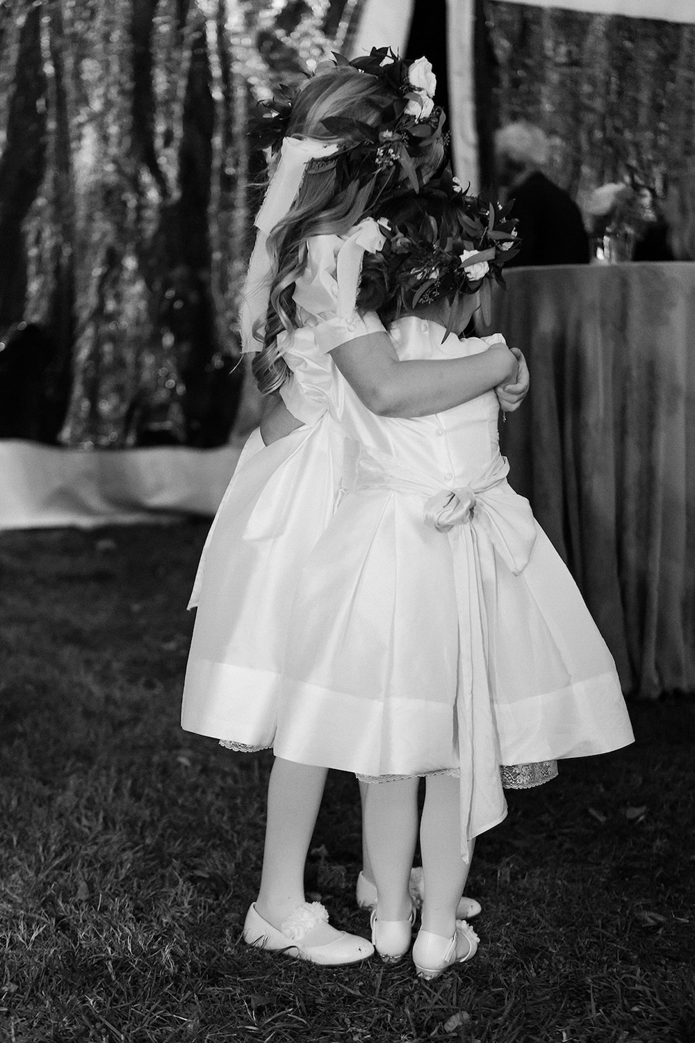 two flower girls hug each other inside wedding tent. Classic timeless winter wedding, woodlawn manor, alexandria va. Sarah bradshaw photography