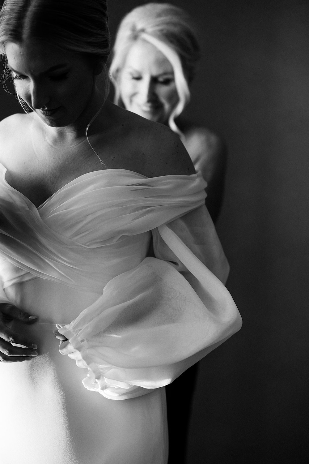 black and white portrait of bride's mother helping her into off shoulders wedding dress. High end hotel ballroom wedding, The Fairmont, Washington DC. Sarah Bradshaw Photography