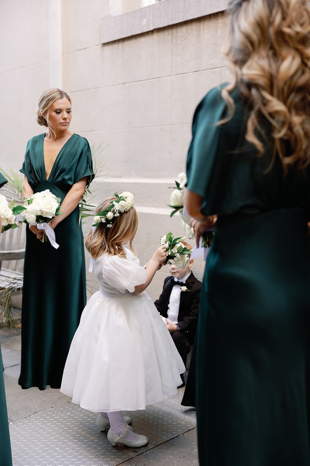 flower girl in floral crown waits with bridesmaids in emerald green dresses. High end hotel ballroom wedding, The Fairmont, Washington DC. Sarah Bradshaw Photography