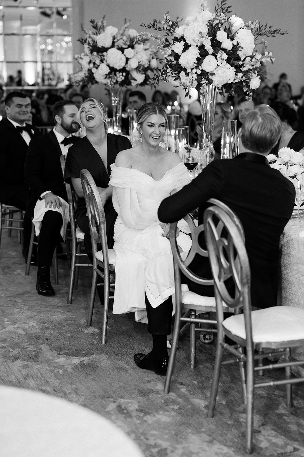 black and white portrait of bride and groom laughing during wedding speech. High end hotel ballroom wedding, The Fairmont, Washington DC. Sarah Bradshaw Photography