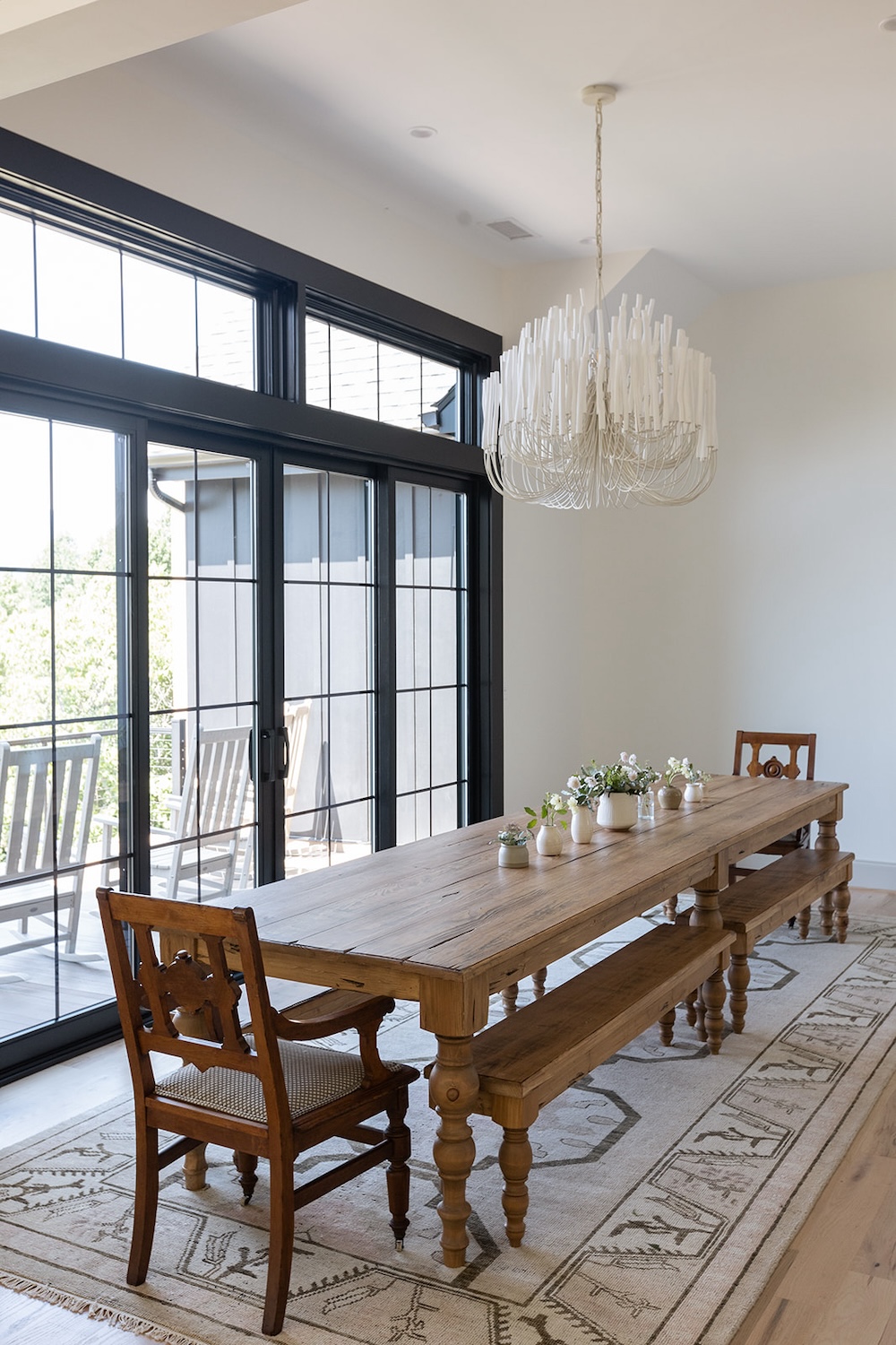 chic dining room, large family style table with bench seating, candle chandelier. Luxury rental property in blue ridge mountains, afton house, sarah bradshaw photography.