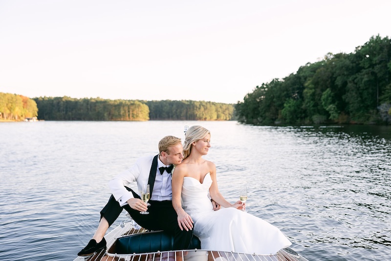 Bride and groom take a sunset ride in vintage boat on lake. Elegant wedding at the Ritz-Carlton Lake Oconee in Georgia. Sarah Bradshaw Photography.