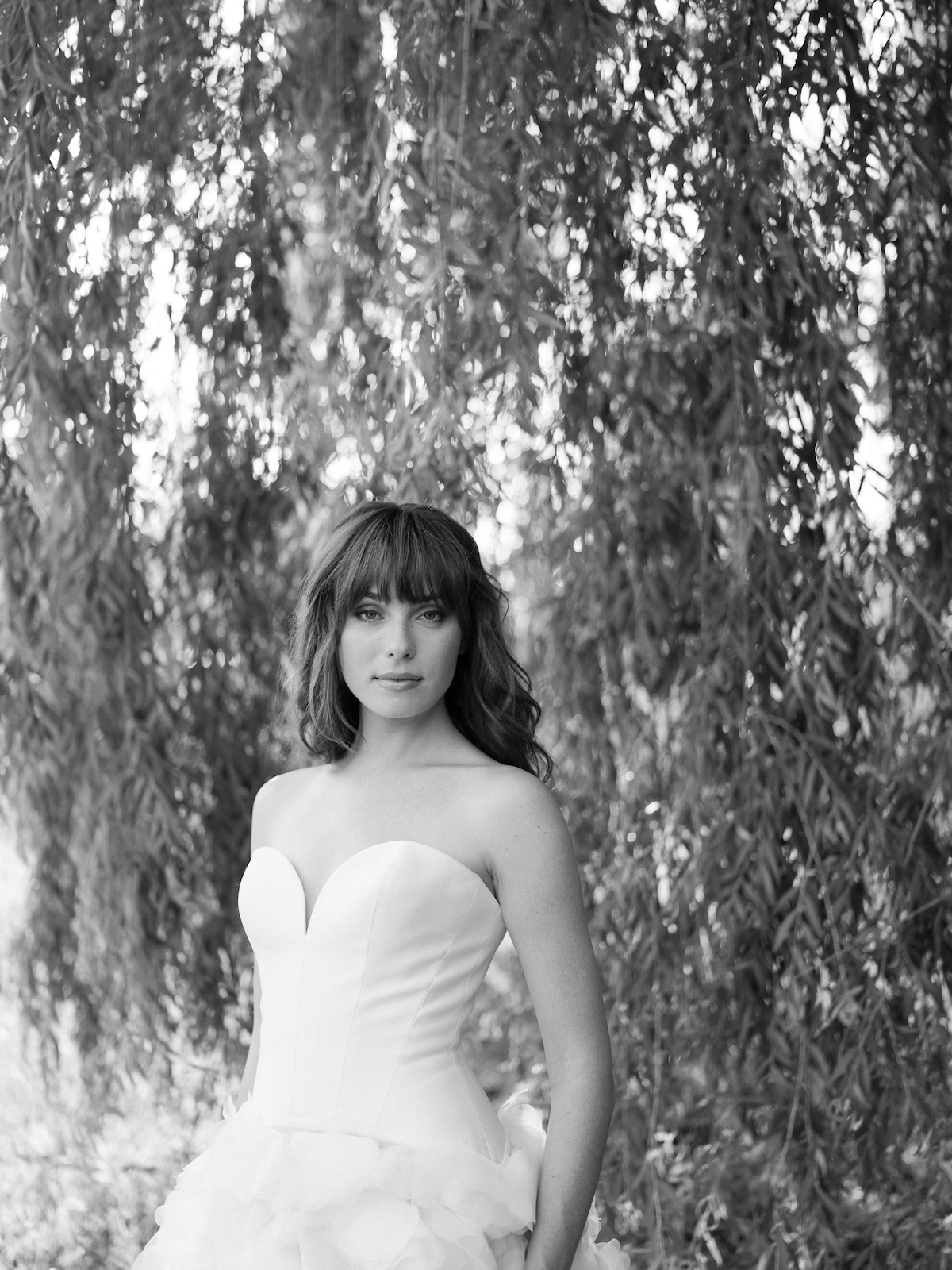 black and white portrait of bride in strapless wedding dress in willow branches. chic equestrian wedding inspiration at Red Fox Inn, Middleburg Virginia. Sarah Bradshaw