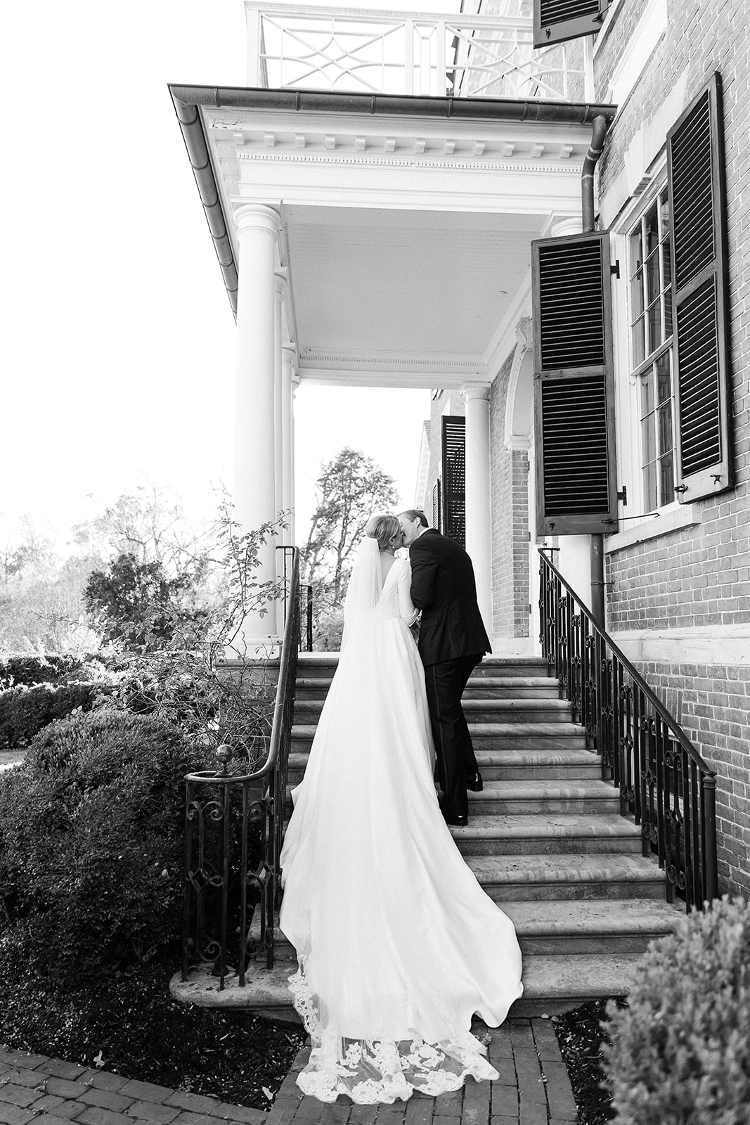 black and white portrait of bride and groom kissing on staircase. Classic timeless winter wedding, woodlawn manor, alexandria va. Sarah bradshaw photography